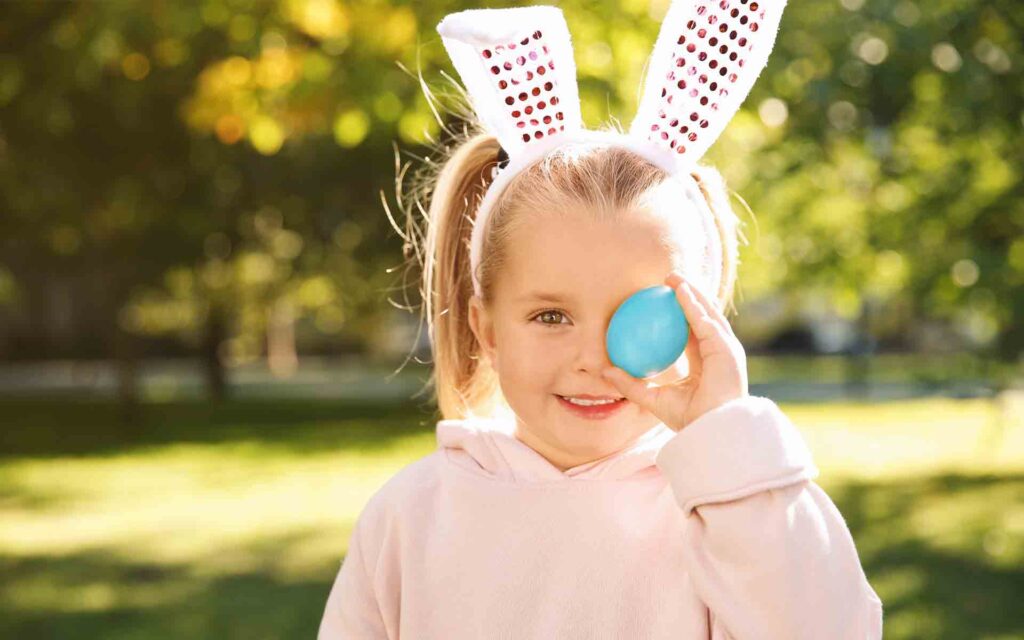 Kind mit Osterhasenohren und Osterei