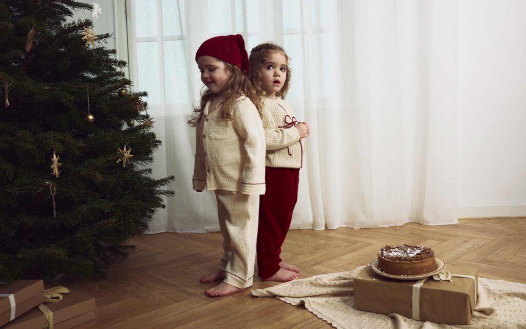 Zwei kleine Mädchen neben einem Tannenbaum