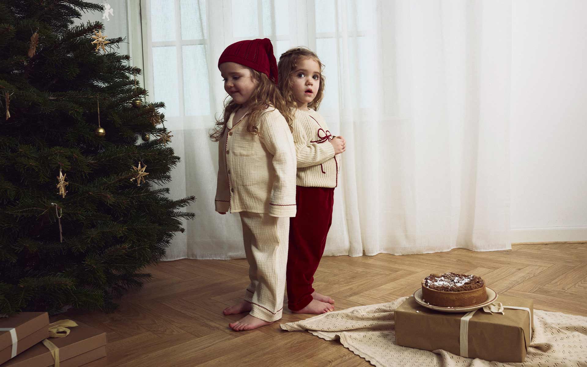 Zwei kleine Mädchen neben einem Tannenbaum