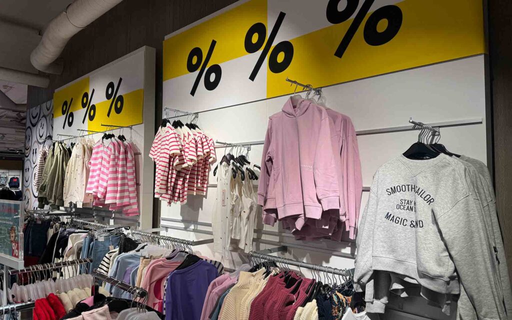 Kinderbekleidung in der KinderWelt, darüber ein Prozenteschild
