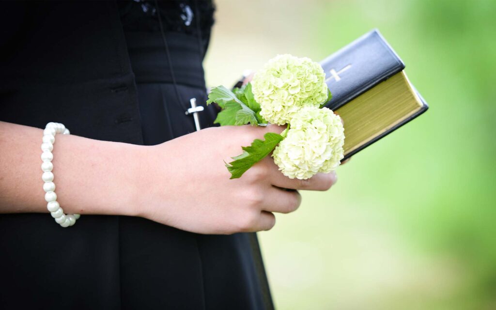 Hände mit Bibel und Blumen