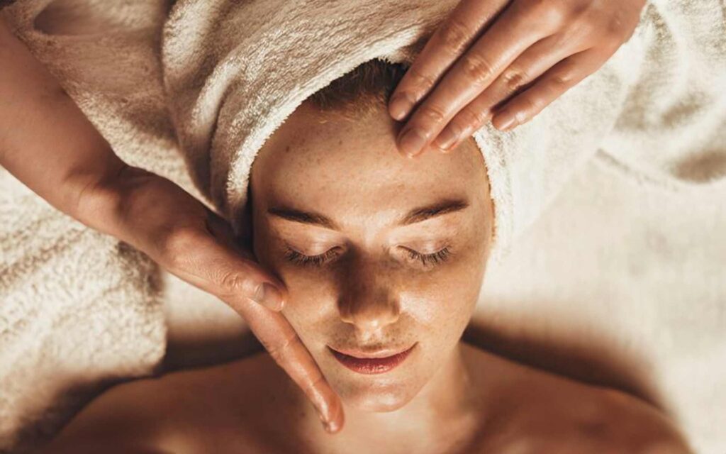 Frau mit Handtuch auf dem Kopf bekommt eine Gesichtsmassage