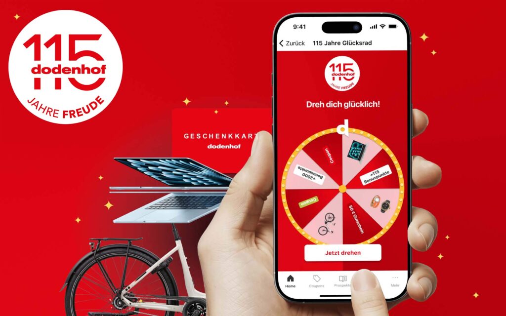 Handy mit dodenhof App und Glücksrad, dahinter ein Laptop und Fahrrad