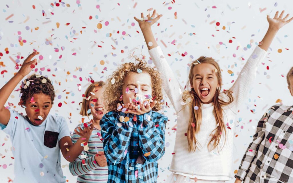 Kinder schmeißen buntes Konfetti in die Luft