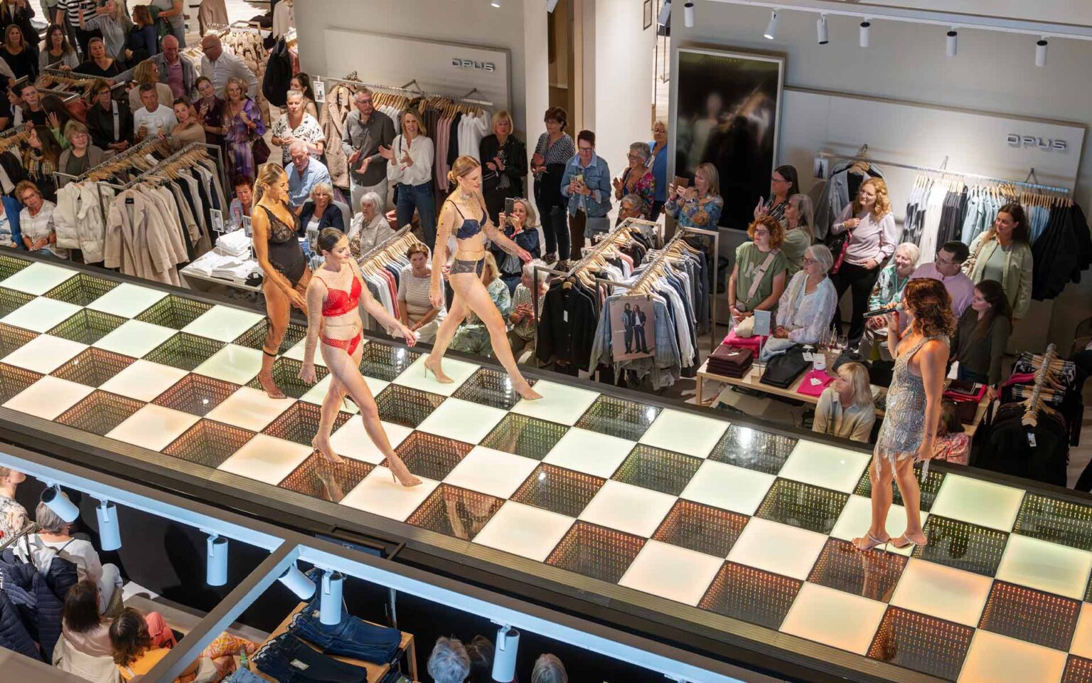 Models und Sängerin auf dem Laufsteg im Schachbrettmuster