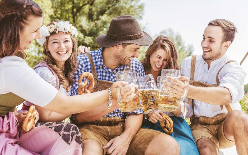 3 Frauen und 2 Männer in Trachten stoßen mit Bier an