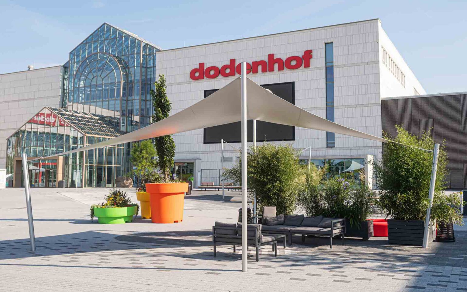die doenhof Plaza im Sommer mit Sonnensegel, Sitzmöglichkeiten und Pflanzen