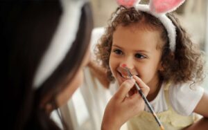 Mädchen mit Hasenohren bekommt das Gesicht bemalt