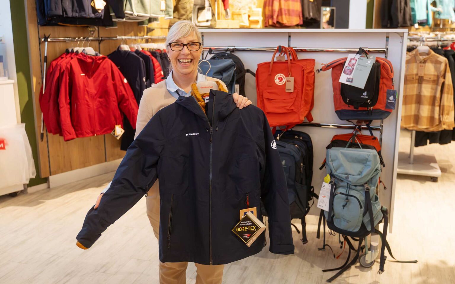 Mitarbeiterin mit einer Regenjacke von Mammut in der Hand