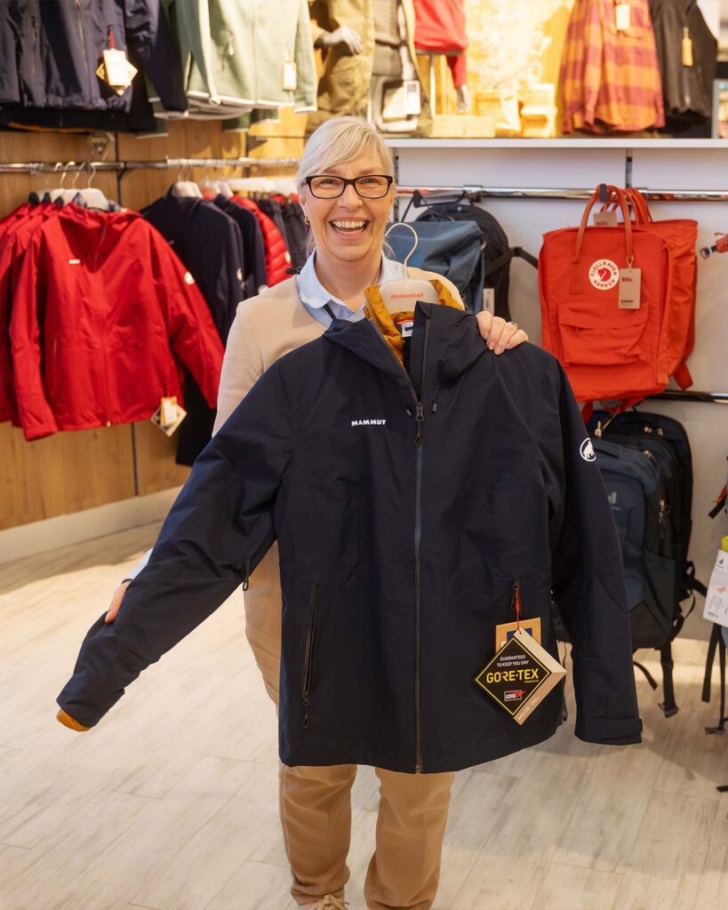 Mitarbeiterin mit einer Regenjacke von Mammut in der Hand