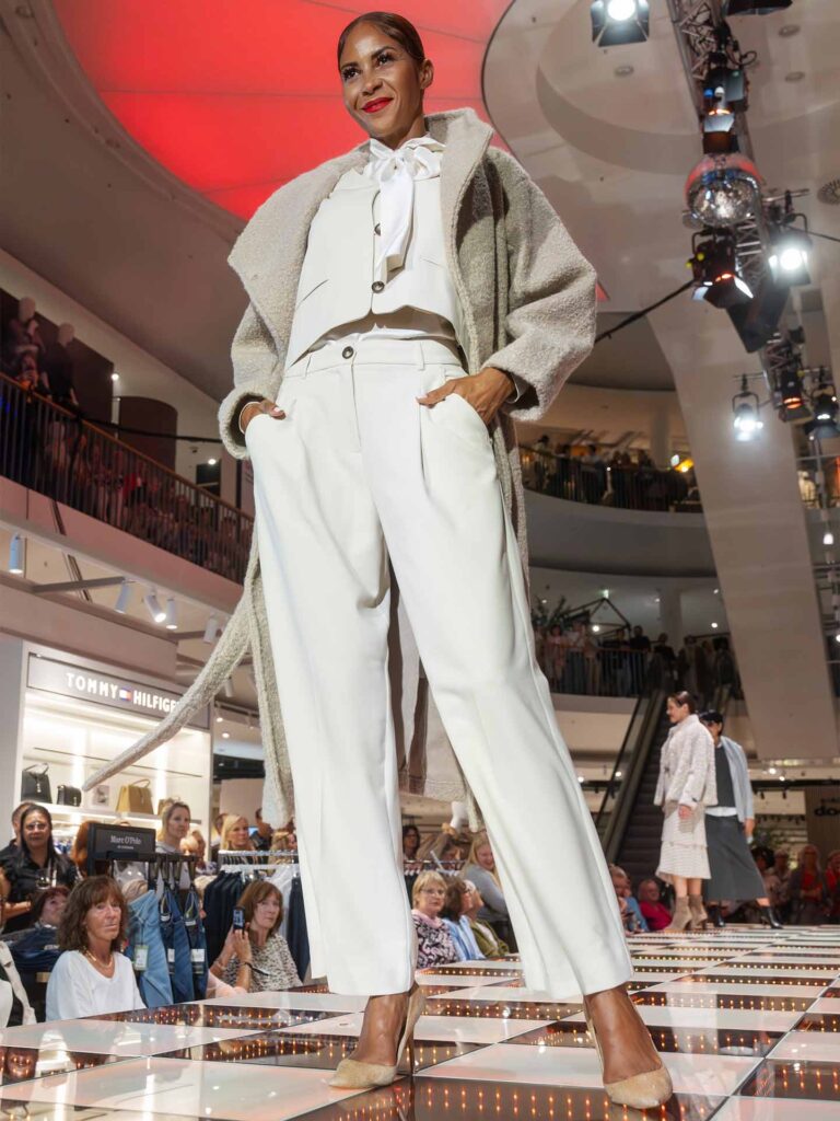 Model mit hellem Winteroutfit auf dem Laufsteg