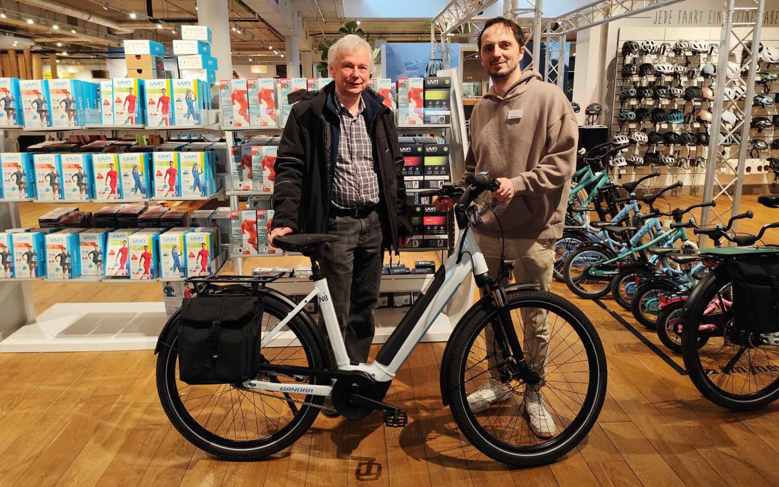 Kunde und Mitarbeiter hinter dem E-Bike in der SportWelt