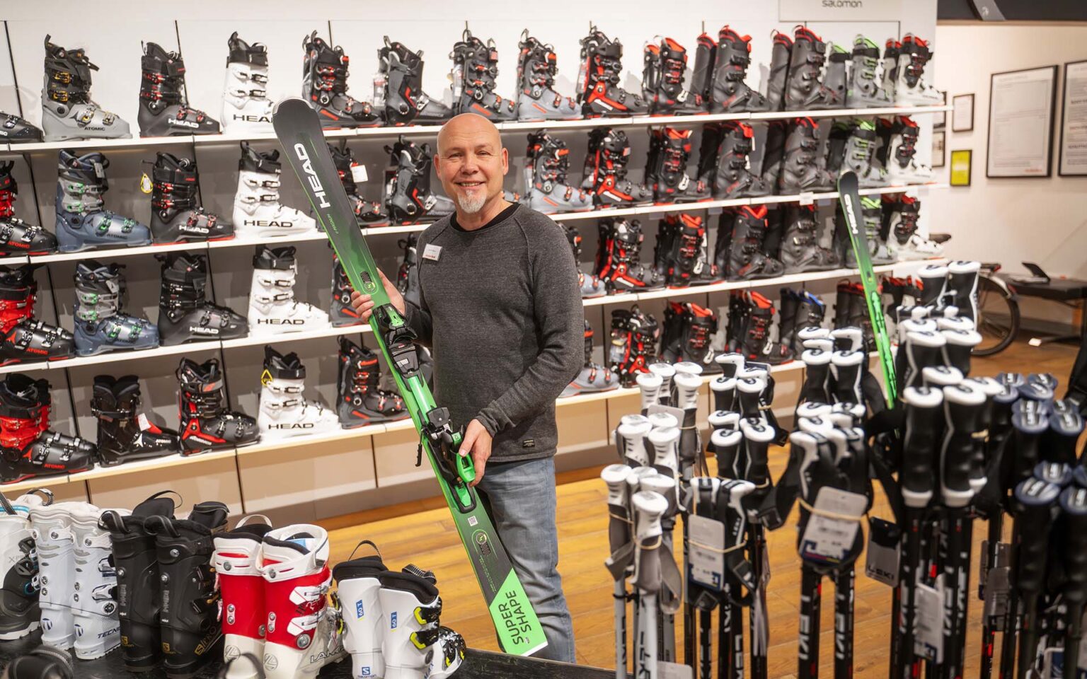 Mitarbeiter hält einen grünen Skier in der Hand Alternativbild