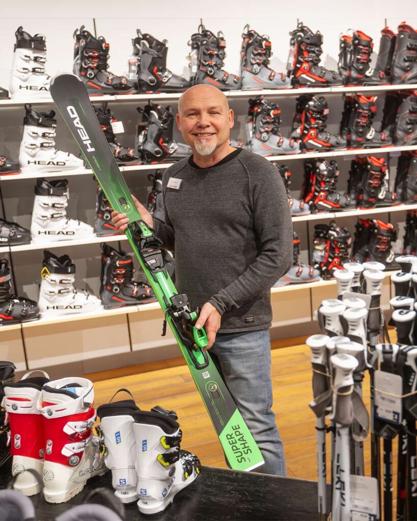 Mitarbeiter hält einen grünen Skier in der Hand
