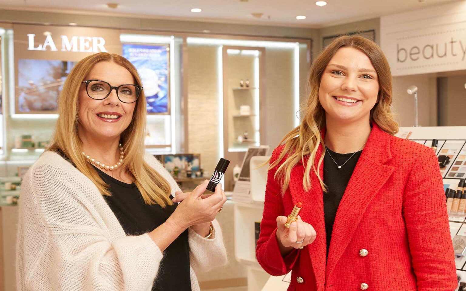 2 Verkäuferinnen aus der Parfümerie mit Lippenstiften in der Hand
