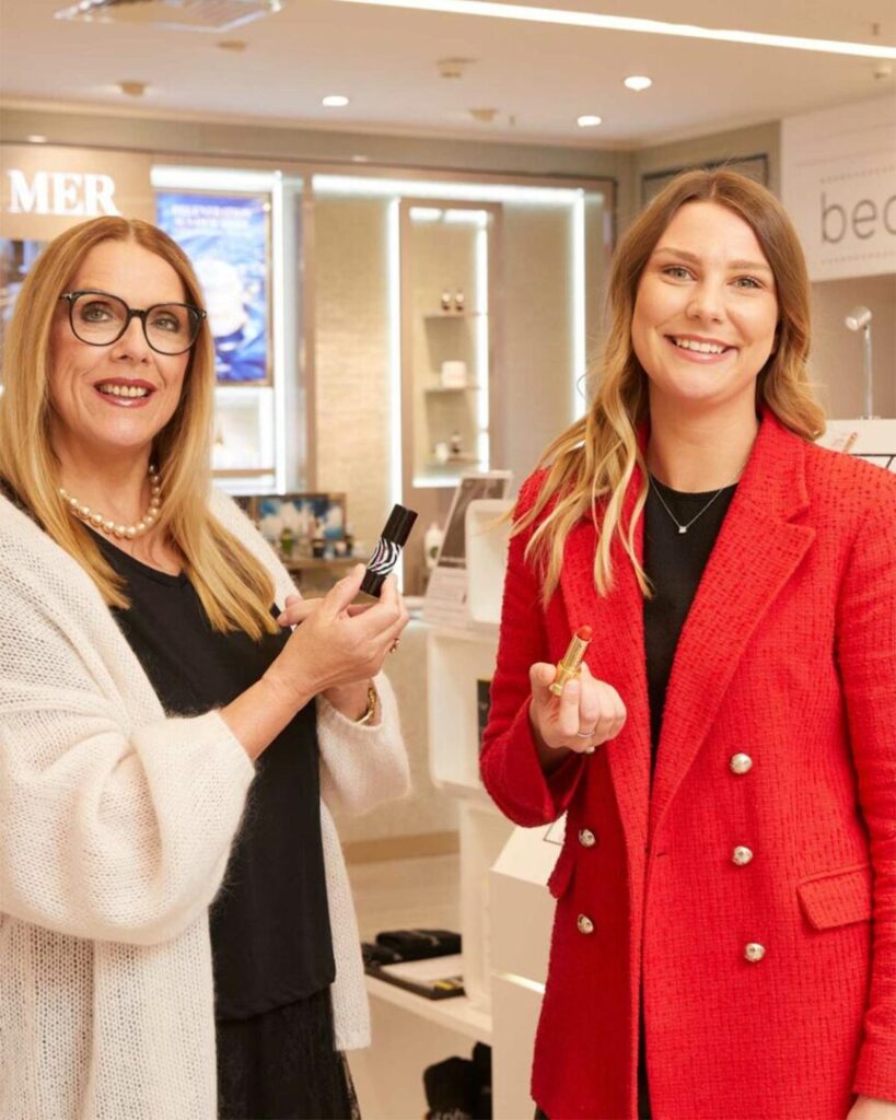 Verkäuferinnen mit Lippenstiften in der Hand in der Beautyabteilung