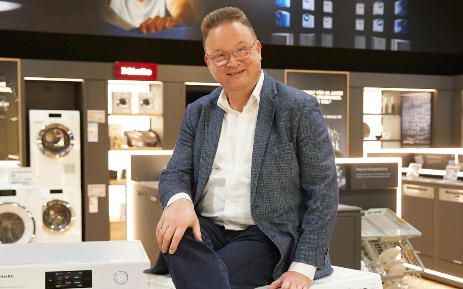 Leiter der Technikwelt sitzend auf einer Miele Waschmaschine