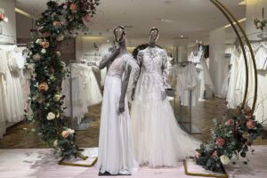 Zwei Figuren mit Brautkleidern in einem Blumenbogen vor dem Brautsalon Posthausen