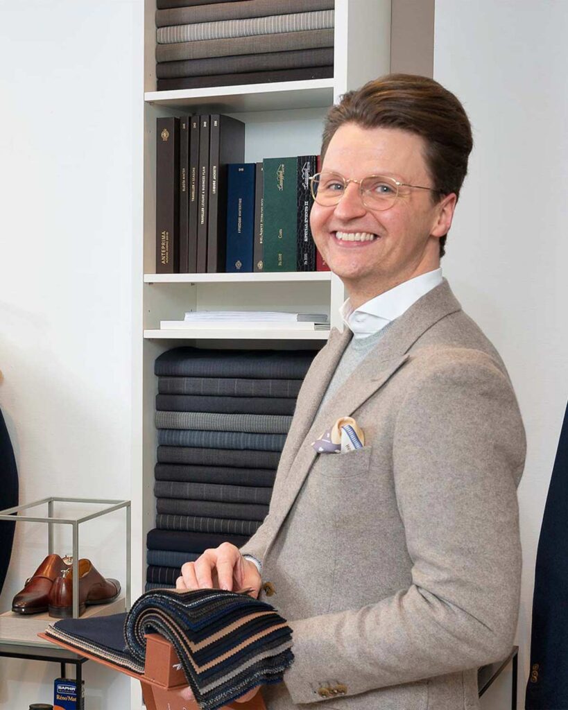 Erstverkäufer der Maßkonfektion in der ModeWelt mit Stoffen in der Hand