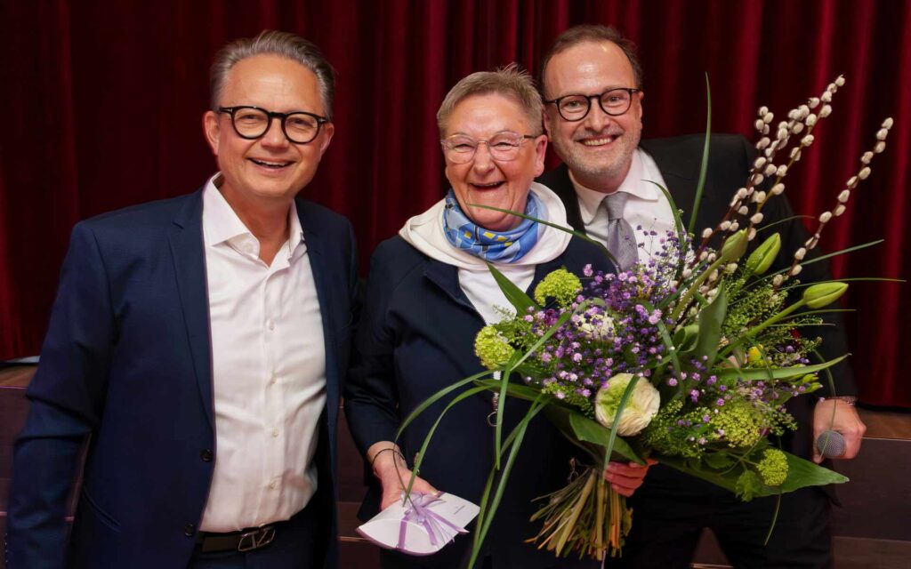 Inhaber, Geschäftsführer und Mitarbeiterin mit Blumenstrauß