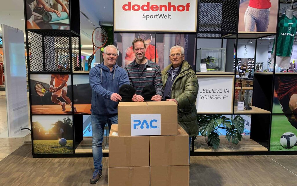 3 Herren mit 5 Kartons Funktionermützen von P.A.C.