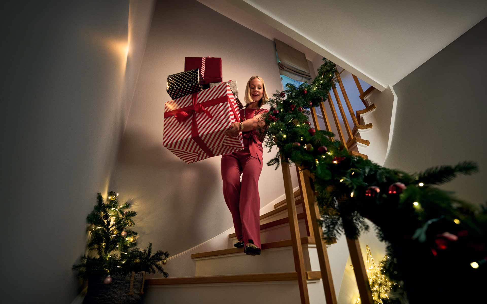 Frau trägt Stapel Geschenke die Treppe herunter