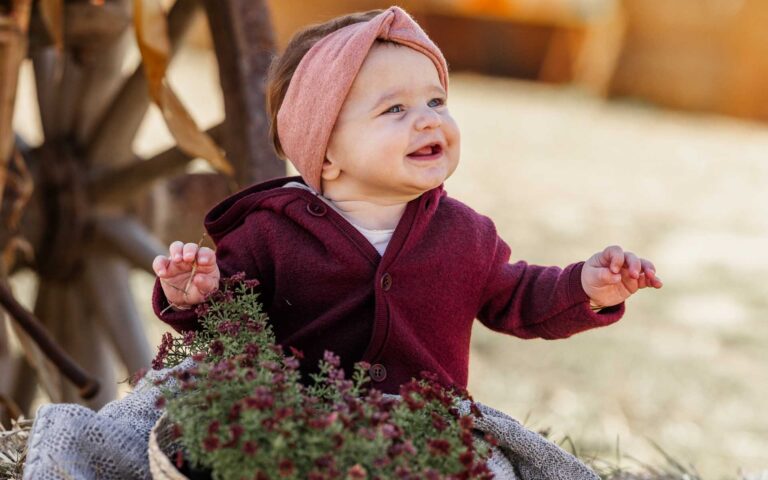 Baby in roter Jacke und rosanem Stirnband