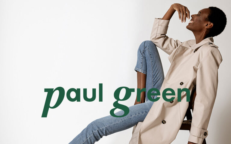 Lachende Frau in Mantel und Jeans mit paul green Logo