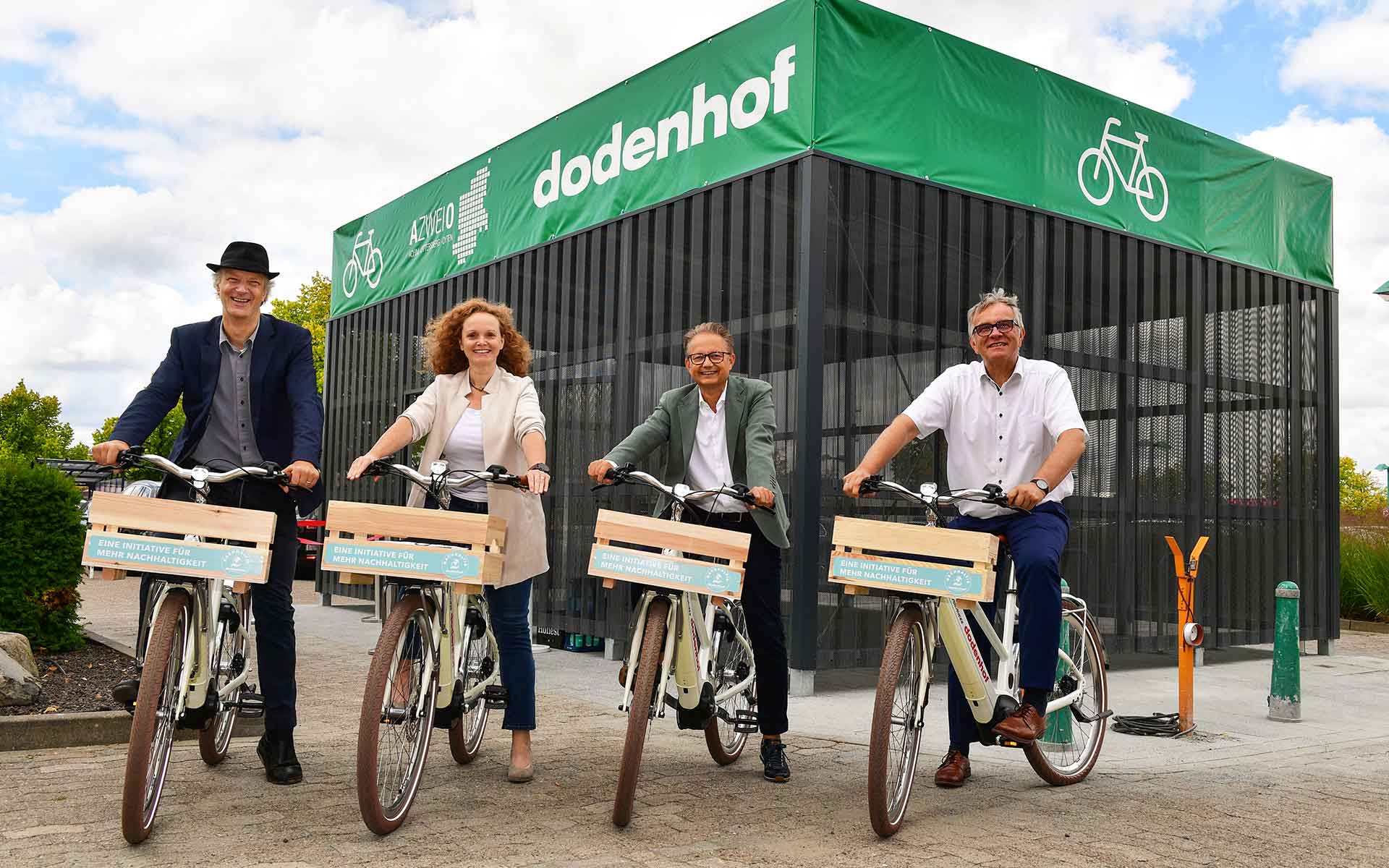 Vier Personen auf Fahrrädern vor der A Zwei O Fahrradbox